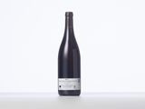 a bottle of wine sitting on top of a table next to a white wall
