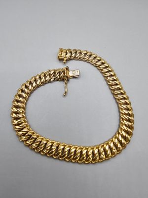 un bracelet à chaîne en or avec un fermoir sur fond blanc