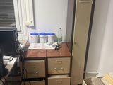 a desk with a computer and a refrigerator in a room