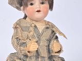 a small doll sitting on the ground wearing a hat and coat