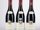 three bottles of red wine sitting next to each other on a table