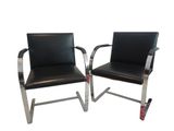 two black leather chairs with chrome legs and a black leather seat