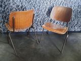 two wooden chairs sitting next to each other in front of a wall