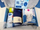 une boîte bleue contenant une bouteille d'eau, un flacon de spray, un tube de dentifrice, une brosse à dents et une brosse à dents