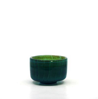 un bol vert posé sur une surface blanche, sur fond blanc