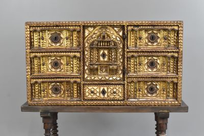 une commode dorée posée sur un socle en bois