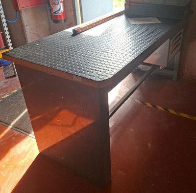 une table de bricolage en métal avec un plateau noir, dans un garage