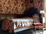 un lit et une chaise dans une pièce dont l'un des murs est tapissé