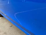 a close up of a blue car parked in a parking lot