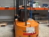 a man standing next to a forklift in a warehouse