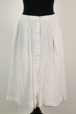 La jupe est blanche et comporte des boutons sur le devant.