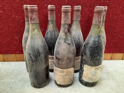 Quatre bouteilles de vin sont posées sur une table devant un mur rouge.