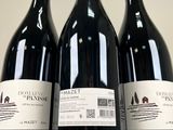 three bottles of red wine are lined up on a table