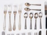 a lot of silver spoons and forks and a cell phone