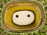 a small white face in the middle of a green bowl