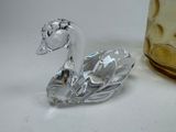 crystal swan figurine sitting next to a glass bottle on a table