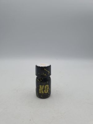 un petit flacon de peinture noire et dorée posé sur une surface blanche