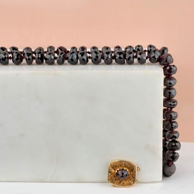 une image représentant un écrin en marbre blanc orné de perles noires et d'un fermoir en or