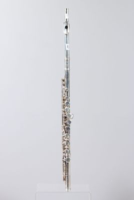 a silver flute on a clear stand against a white background
