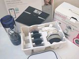a white box with a camera, a bottle, and other items sitting on a table