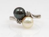 a close up of a pearl and diamond ring on a white surface
