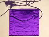 a purple bag with a tassel on it on a table