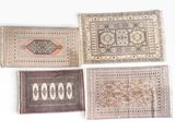 quatre tapis de couleurs et de motifs différents sont disposés sur une surface blanche