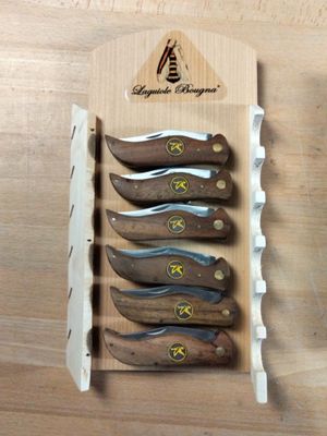five knives in a display case on a wooden table