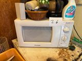 a microwave sitting on top of a counter with a basket on top of it