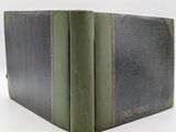 an old book with a green cover sitting on top of a white table