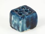 a small blue object with holes in it on a white surface