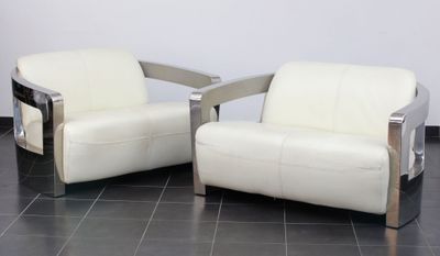 une paire de fauteuils en cuir blanc et chromé posés sur un sol en carrelage noir