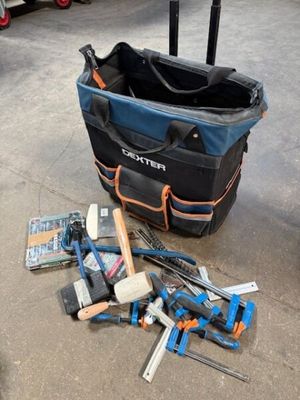 un sac rempli d'outils posé par terre à côté d'une valise