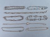 plusieurs types de bracelets et de chaînes en argent posés sur une table