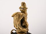 a gold figurine of a man sitting on top of a clock