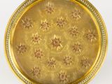 une assiette ancienne dorée, ornée d'étoiles sur un fond blanc