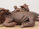 une statue représentant une vache sur laquelle est assis un groupe de personnes