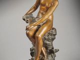 an image of a bronze statue of a woman sitting on a rock