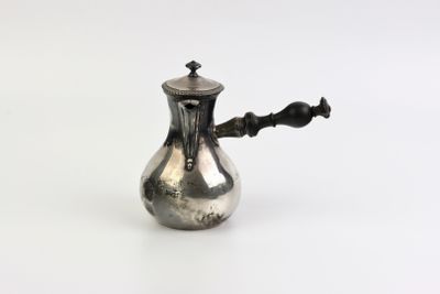 une théière ancienne en argent, avec une anse noire sur fond blanc