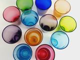 several different colored glasses are arranged in a circle on a white surface