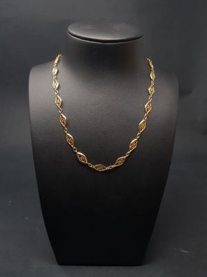 un collier à chaîne en or sur un mannequin, sur fond noir