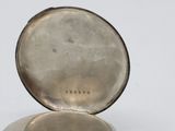 an old silver pocket watch sitting on top of a white surface