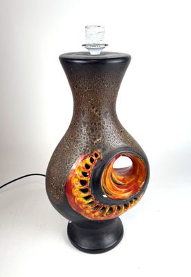 un vase noir et orange surmonté d'une lampe