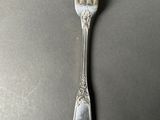 an old silver fork on a table with a spoon on it