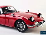 a red toy car that is sitting on a white surface