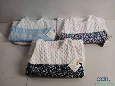 trois bavoirs pour bébé sont posés sur un sol carrelé