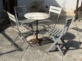 une table et des chaises sur une terrasse, avec un chat assis dessus
