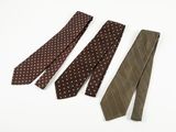 three ties on a white surface one has a brown and white polka dot pattern