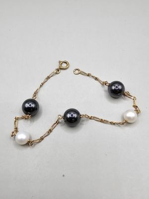 un bracelet noir et blanc orné de perles, monté sur une chaîne en or