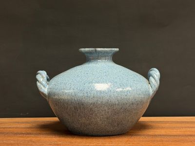 a blue vase sitting on a wooden table with a black background